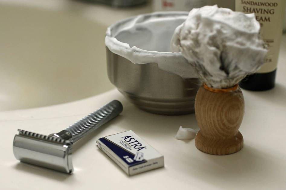 Close-up of luxurious shaving cream lather with brush on marble surface